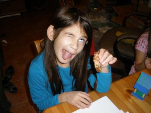 Little girl sticking out her tongue and making a face after taking a taste of fruitcake.
